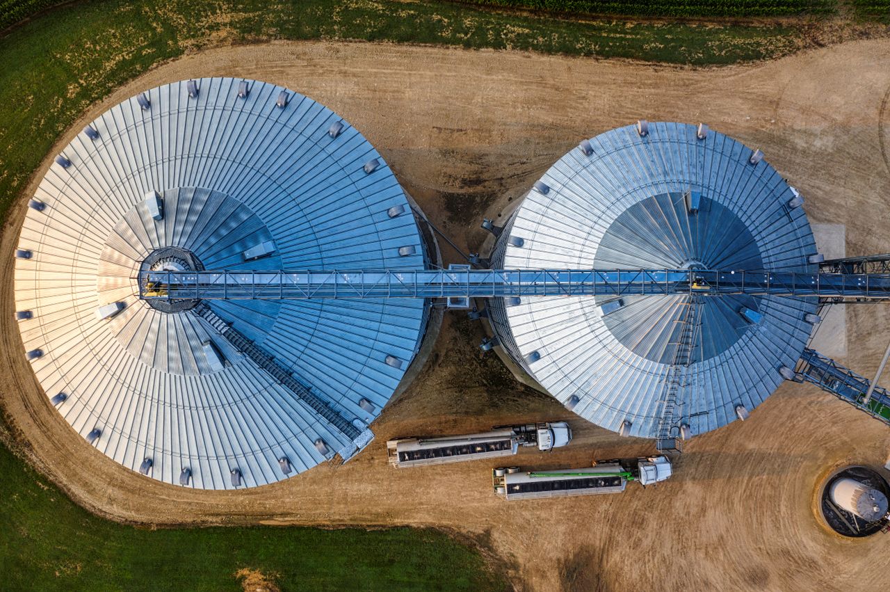 Drone view of two large industrial silos with transportation trucks in Minnesota.