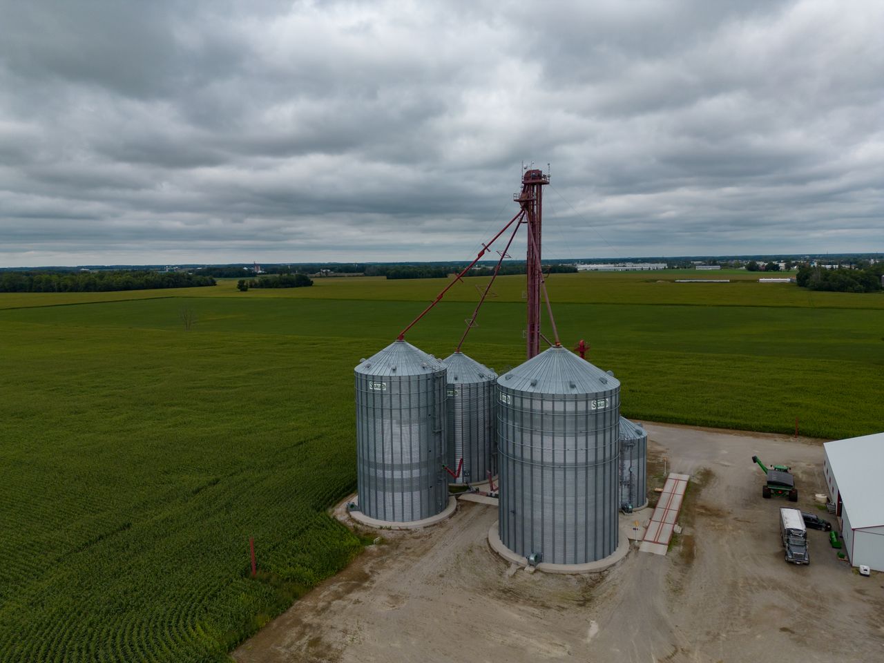 Aerial shot of grain silos amidst sprawling fields under a cloudy sky in Stratford, Ontario.