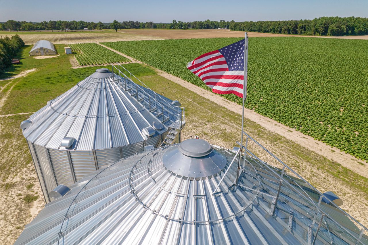 Aerial shot of grain silos on American farmland in North Carolina with a waving US flag.